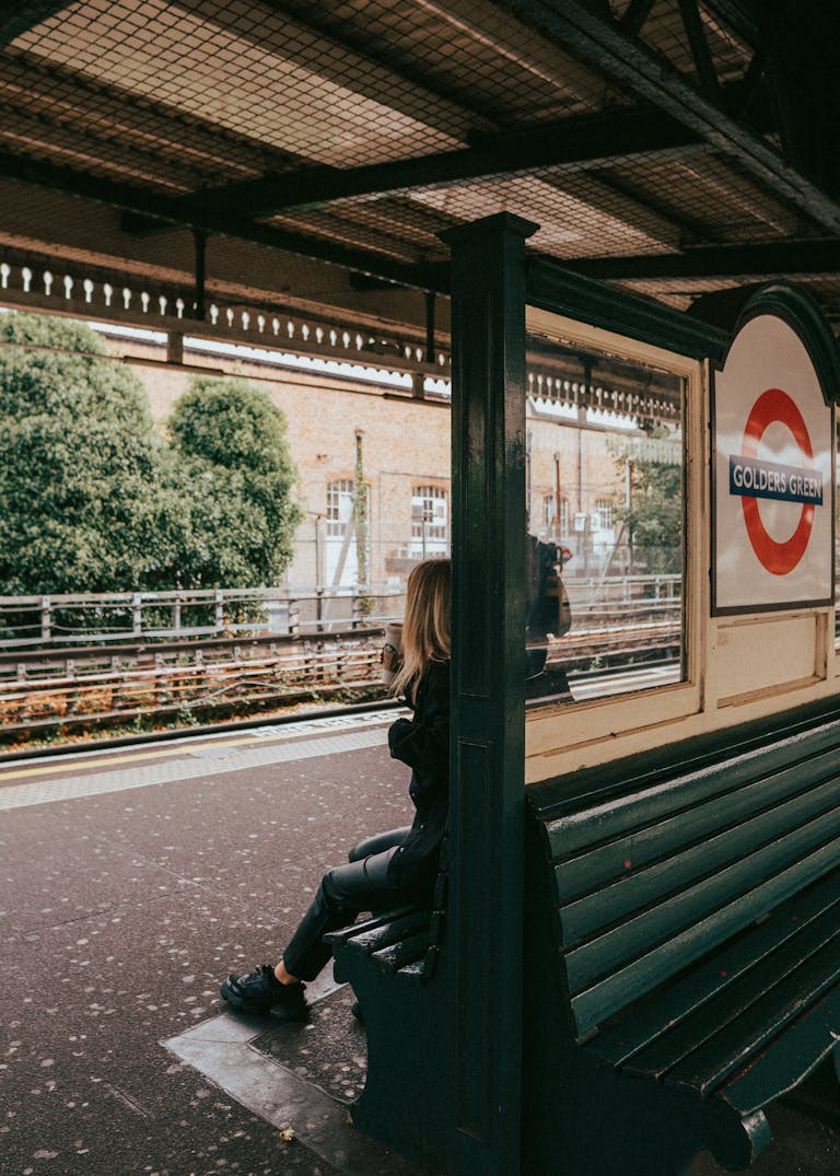 Woman sitting at Golders Green Tube station, capturing urban London life.